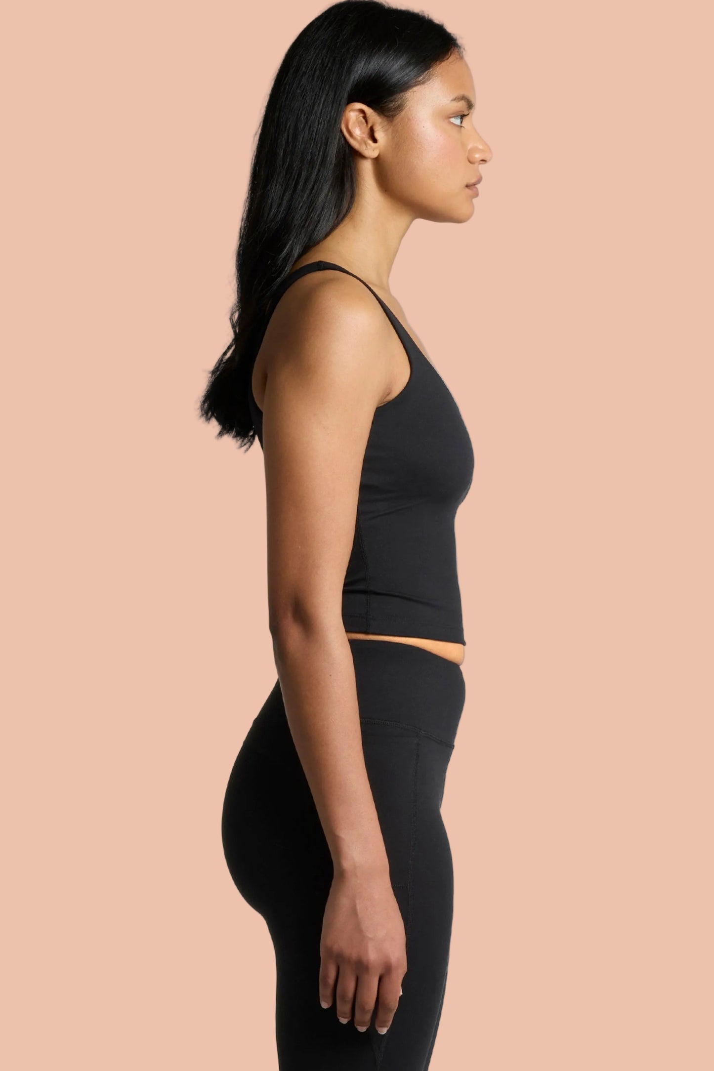Woman wearing Meraki Beach MAREA Active Bra Tank Top in black, PFAS-free sustainable activewear made from recycled nylon for yoga, Pilates and everyday wear