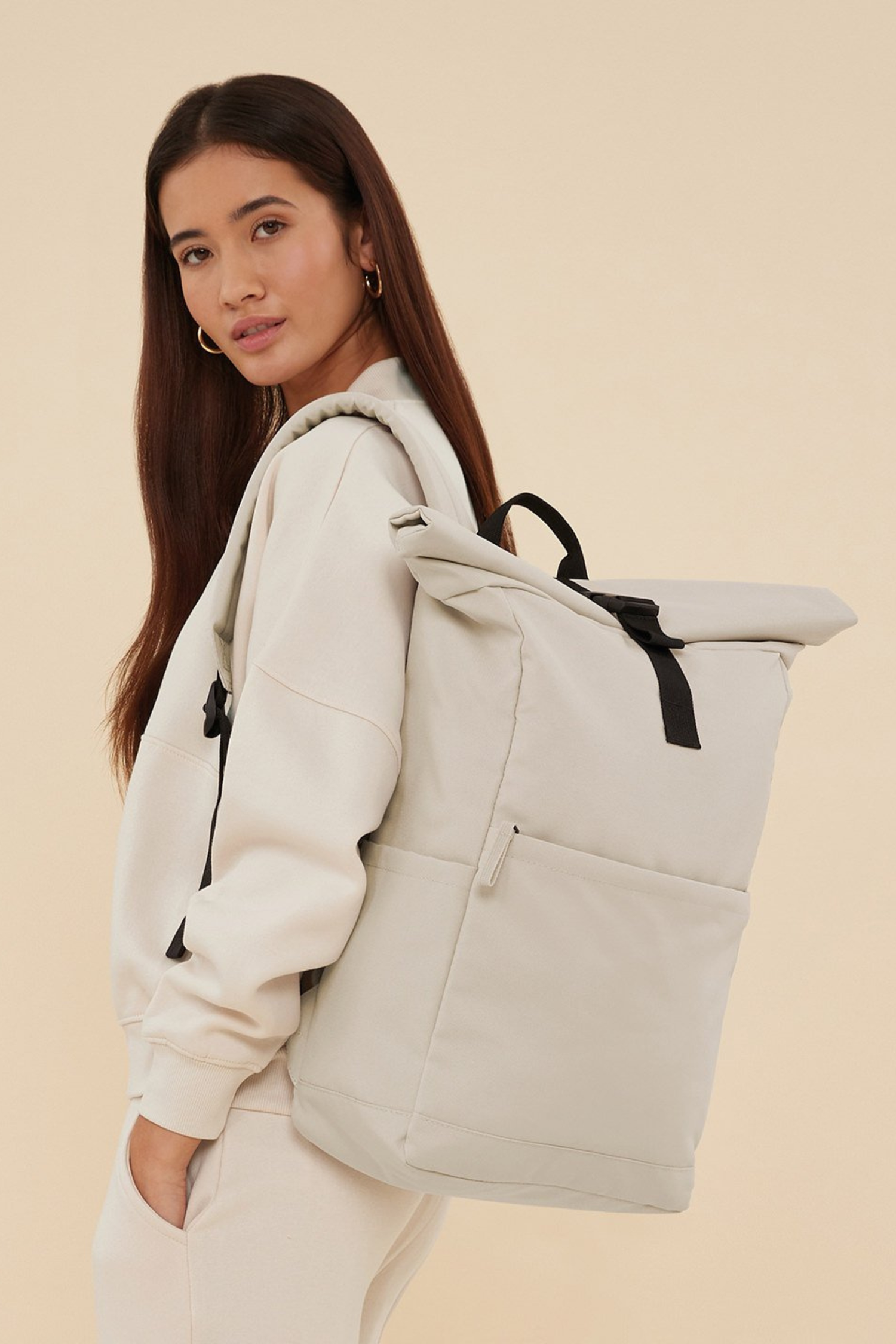 Woman with the Meraki Beach AVENTURA unisex roll-top backpack in Sandstone, minimalist sustainable bag designed for everyday adventure.