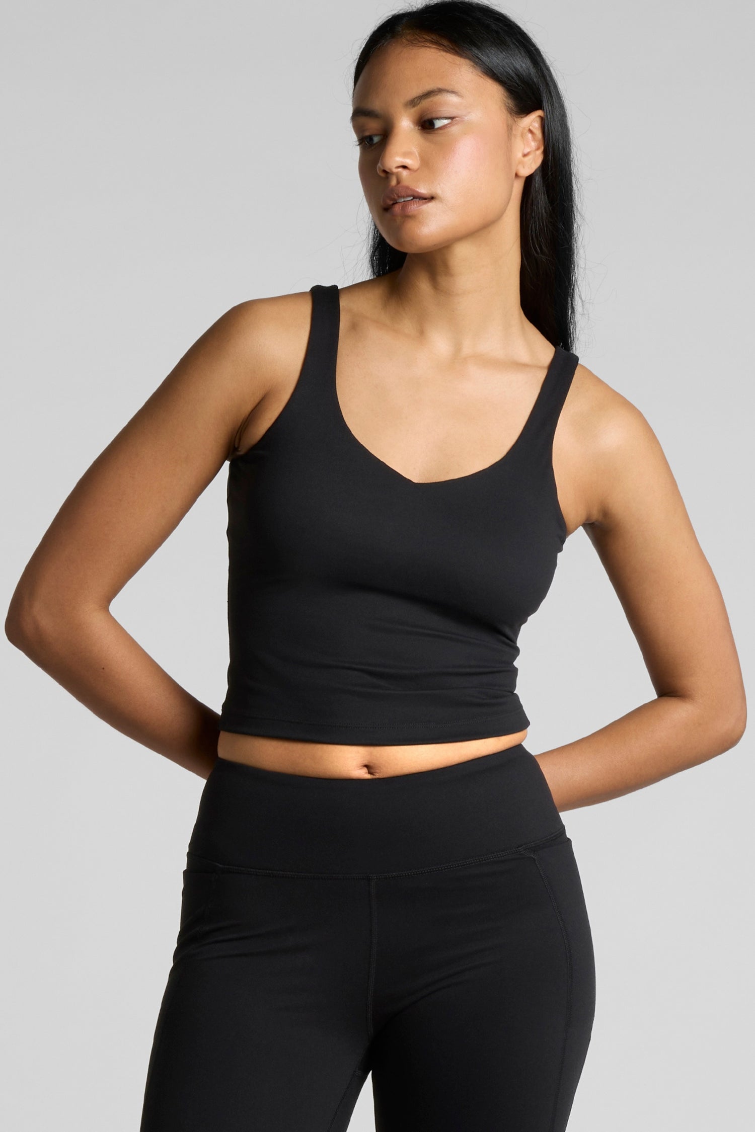 Woman wearing Meraki Beach MAREA Active Bra Tank Top in black, PFAS-free sustainable activewear made from recycled nylon for yoga, Pilates and everyday wear