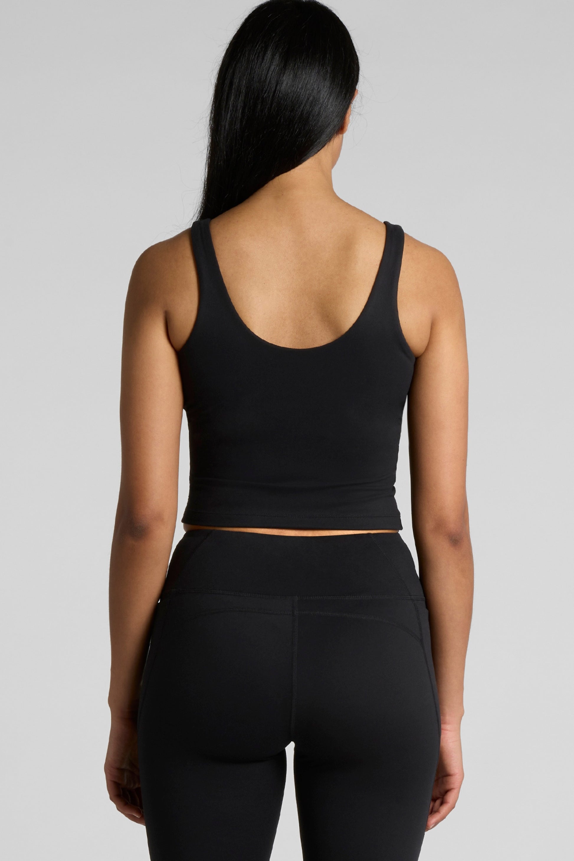 Woman wearing Meraki Beach MAREA Active Bra Tank Top in black, PFAS-free sustainable activewear made from recycled nylon for yoga, Pilates and everyday wear