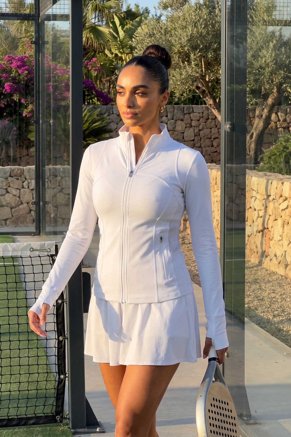 Woman playing padel and wearing the PALMA Women’s Recycled Sports Jacket in White by Meraki Beach – sustainable high-stretch activewear made from recycled plastic bottles